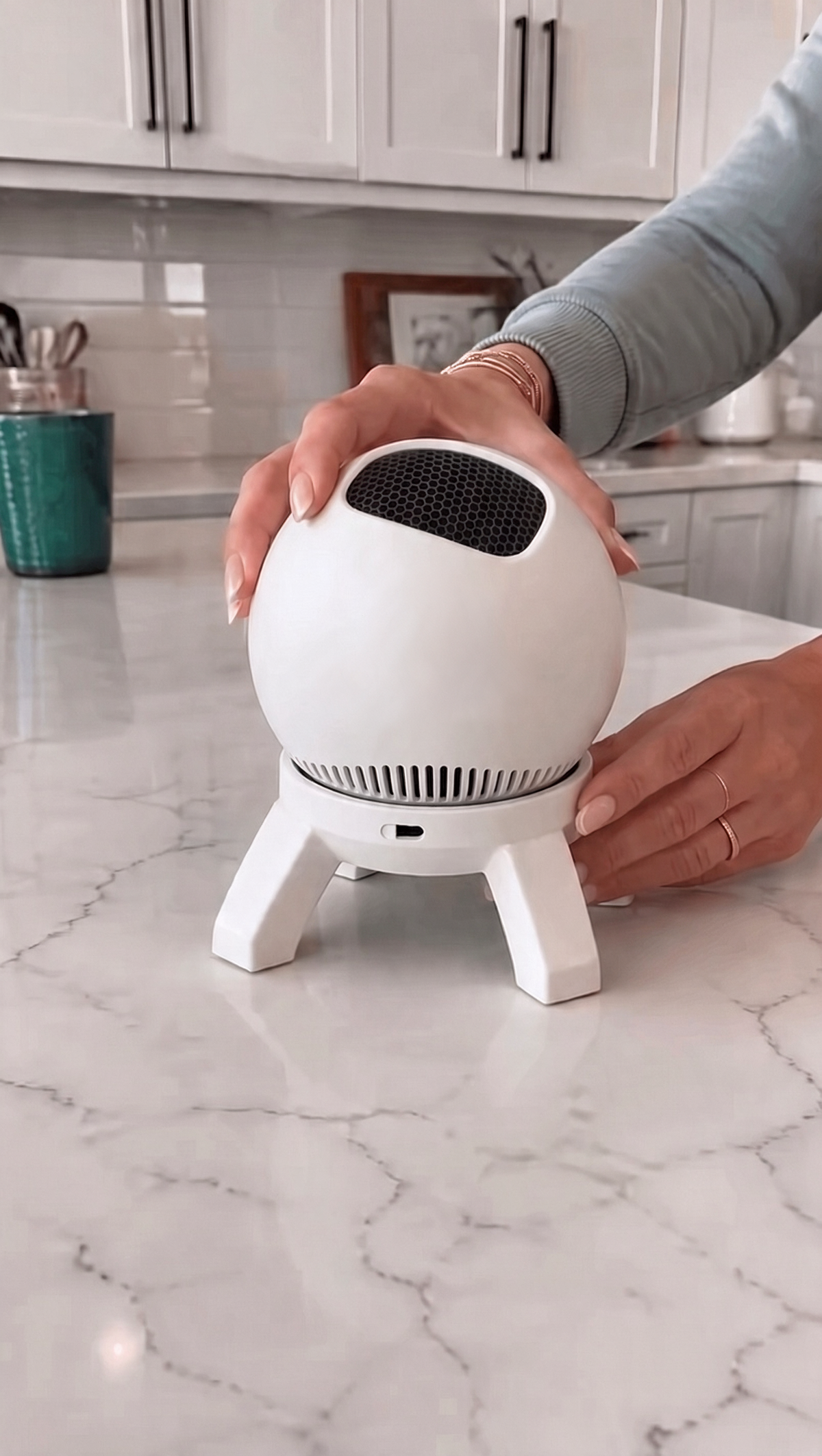 Lumen Orbit Room Projector in plain white, with black honeycomb lens and four-leg stand, on a marble kitchen counter