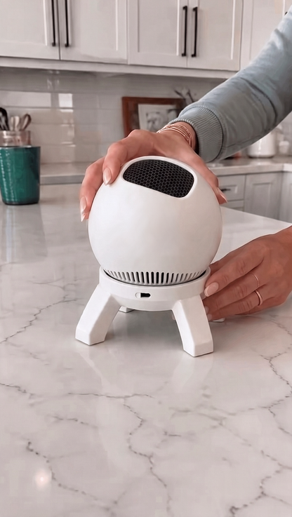 Lumen Orbit Room Projector in plain white, with black honeycomb lens and four-leg stand, on a marble kitchen counter